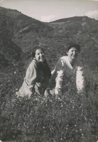 Two smiling girls sitting in a field.