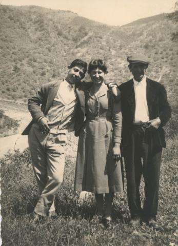 Vittoria smiling with a younger and an older man, their arms over each others' shoulders.