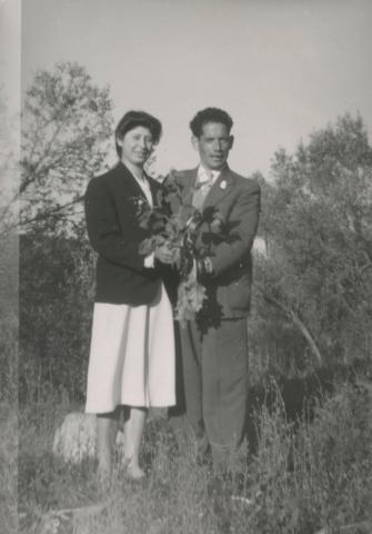 Vittoria with a young man in a suit holding flowers together.