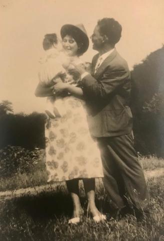 Yellowed photo of a joyful couple embracing a small child.