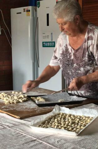 Present-day photo of Vittoria with a tray of gnocchi. Another tray full of gnocchi is displayed in the foreground.