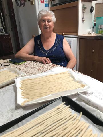 Present-day photo of Vittoria seated behind a tray filled with long lengths of pasta.