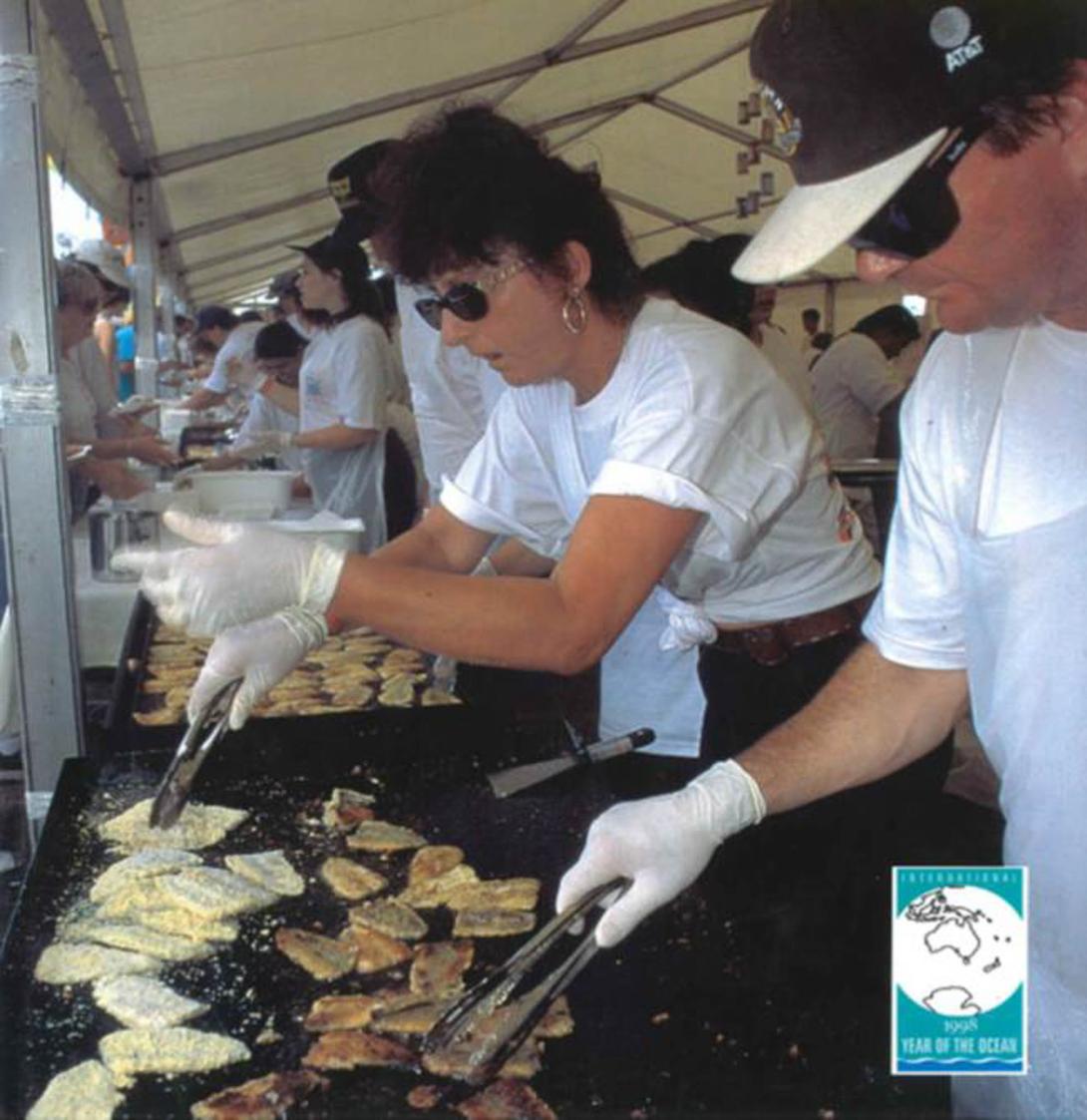 Rosa works in a long line of others in a marquee grilling and serving patrons.