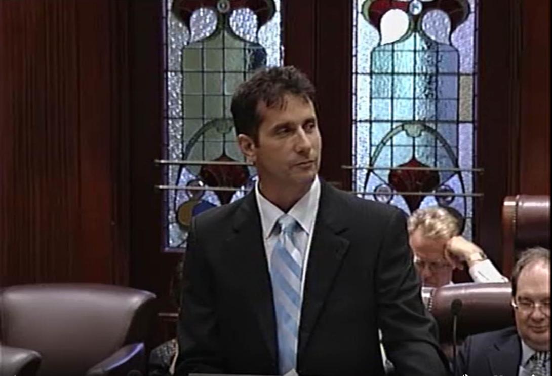 Paul in a suit in Parliament, some stained glass windows behind.