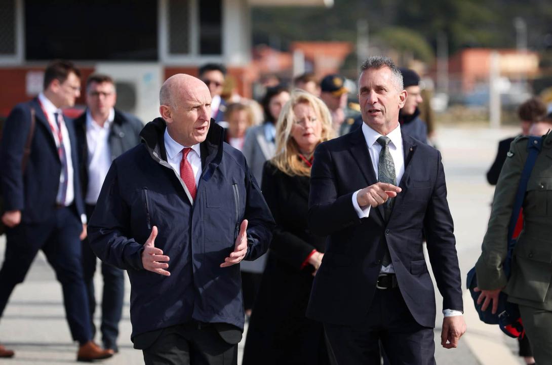 Two men wearing suits in an important discussion as they walk a busy street.