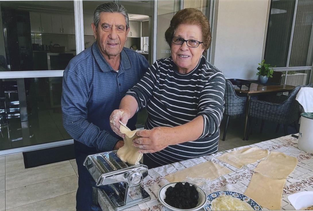 Carmela feeds dough into a pasta press.