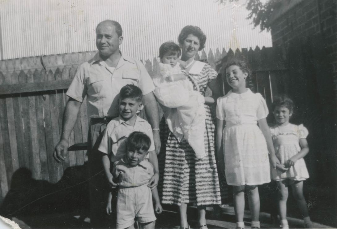 A candid shot of the big family in front of a picket fence.