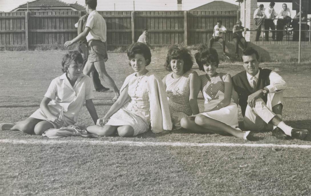 A well-dressed group of teens sitting on the grass.