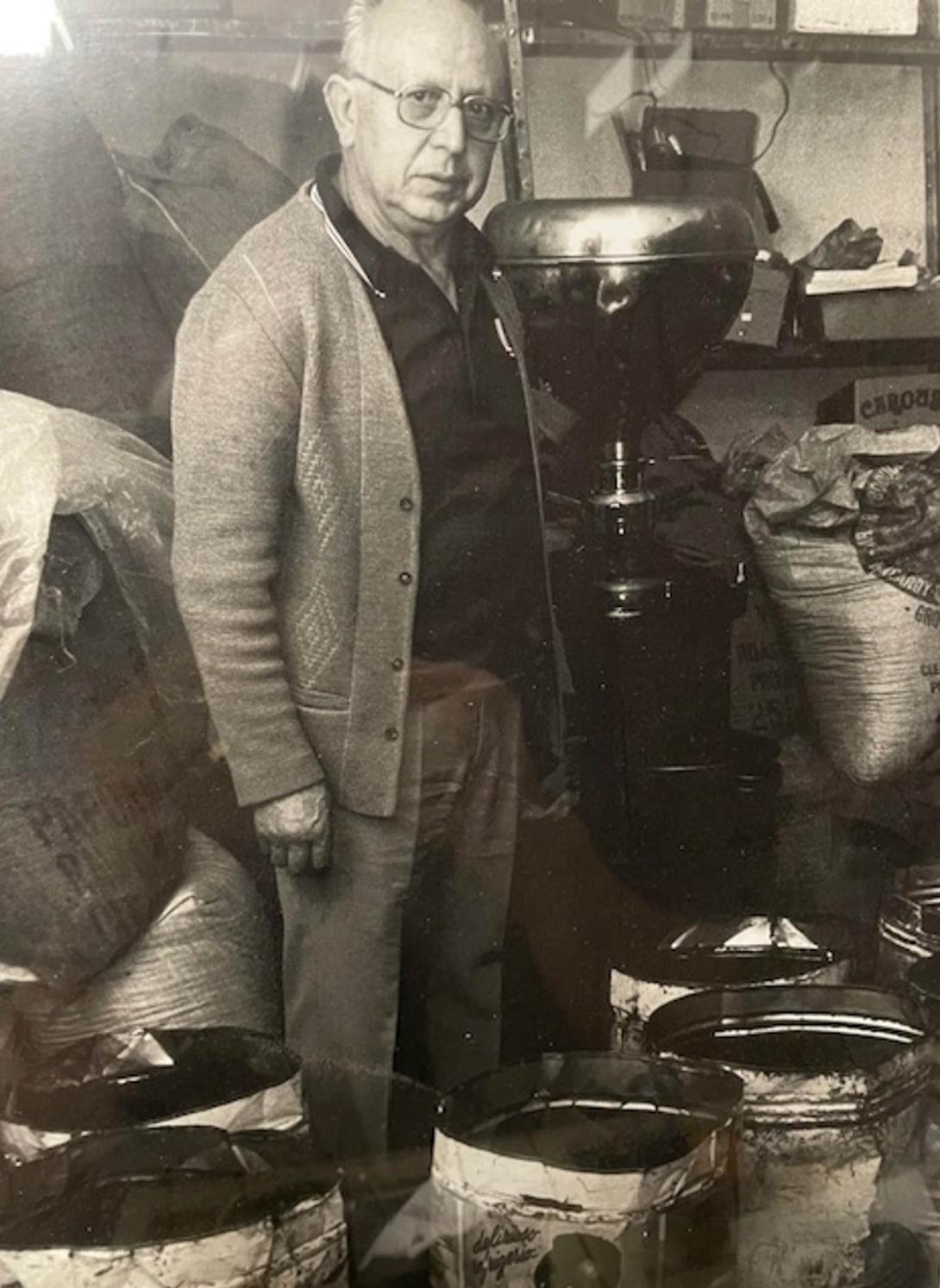 The man is surrounded by big bags of coffee beans.