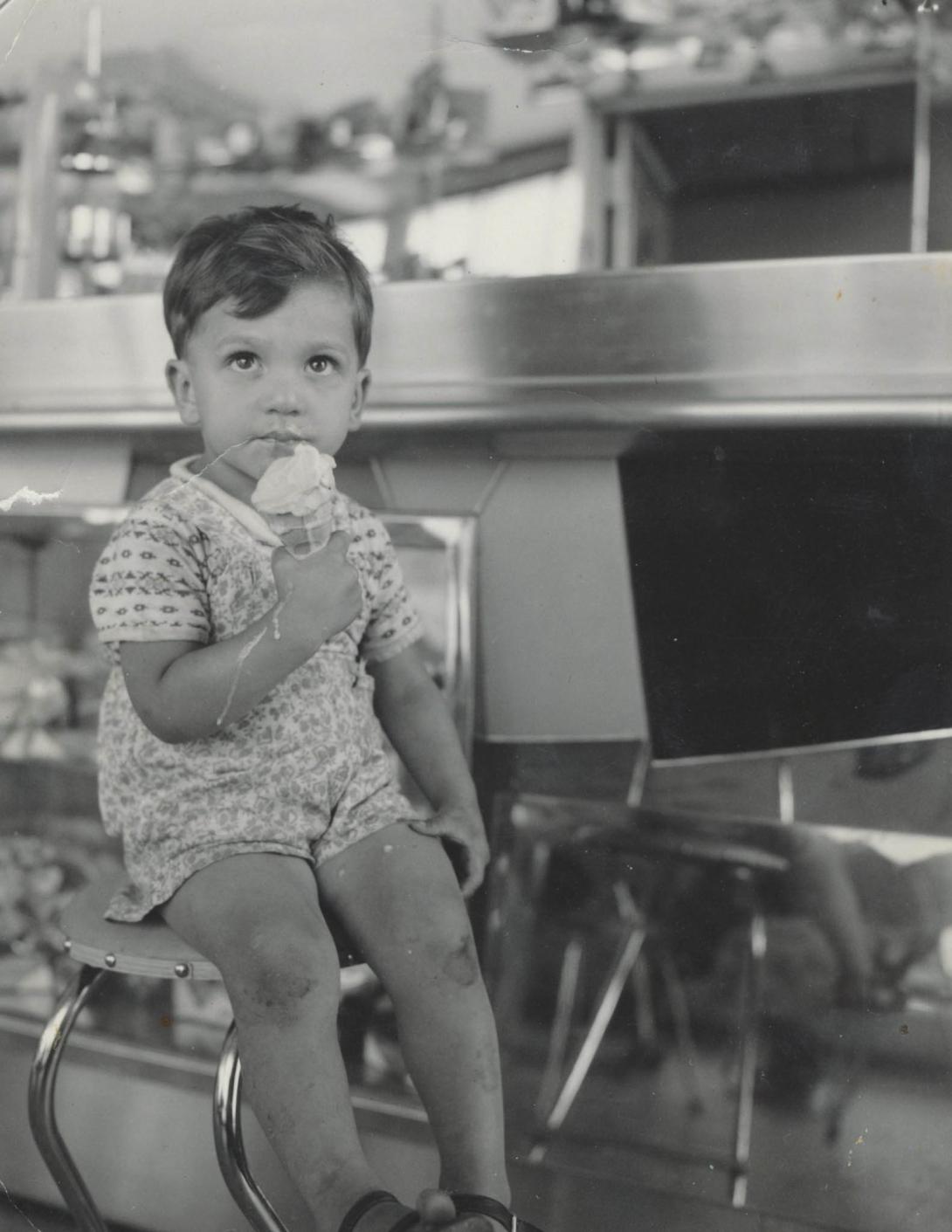 Melted ice cream drips down the arm of the small boy.