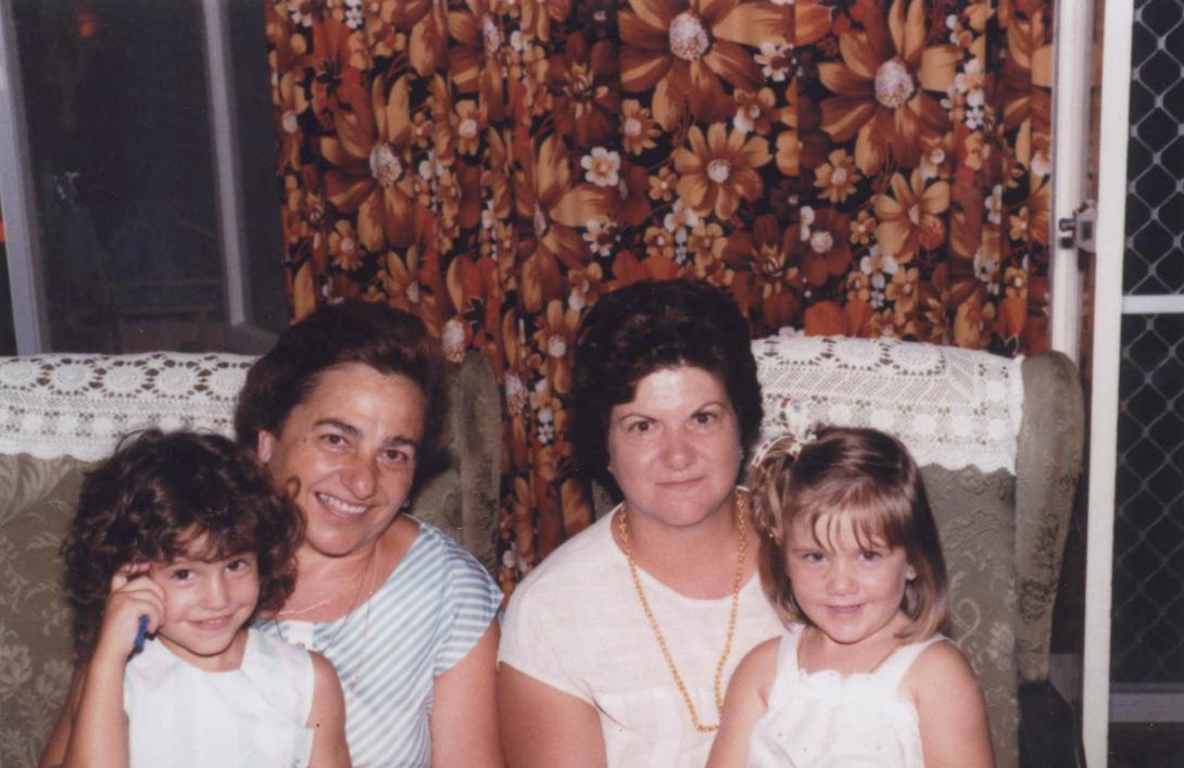 Two grinning children sit on their mothers' laps.