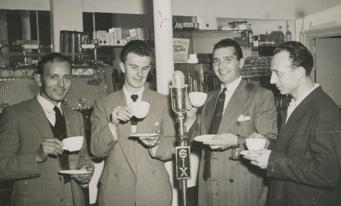 The four men now sip their coffee around the microphone.