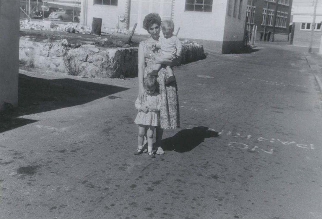 The children look down at the ground as Maria lifts the smallest up for the camera.