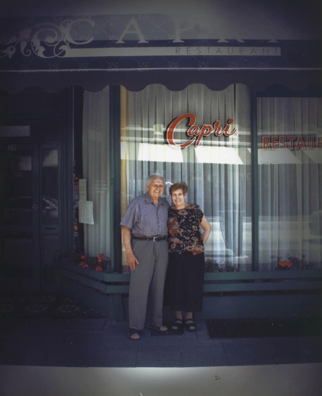 A more recent photo of the couple, now older, happy in front of the restaurant.