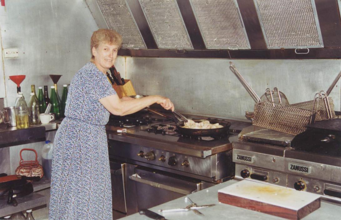 Bottles of oil can be seen behind Maria in the large kitchen.