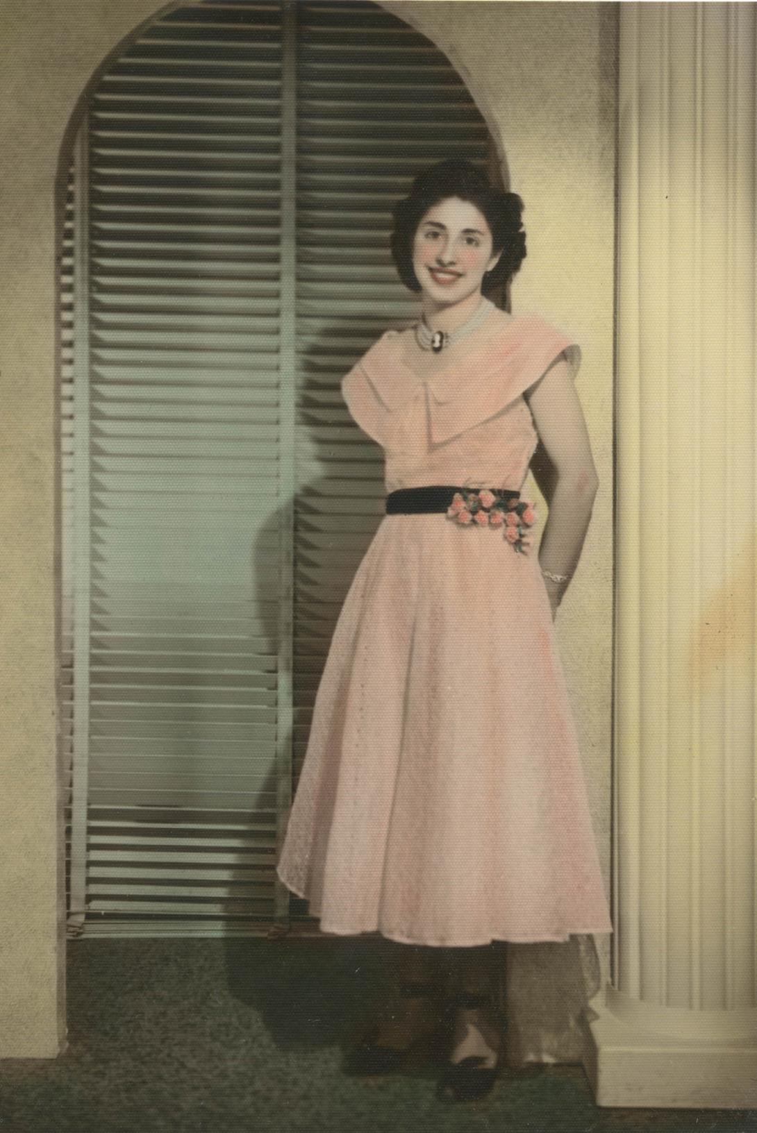 Mary's gown is a pale pink with a black belt and pink flowers at the waist.