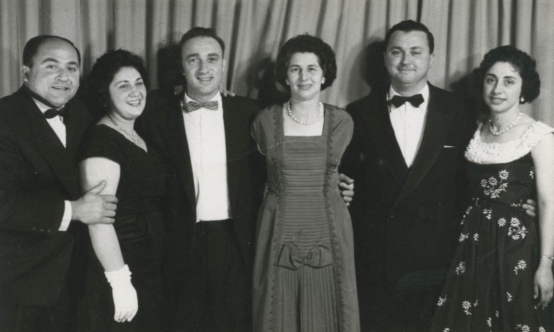 Three men in black suits and bow ties with three women in dresses of different styles and colours.