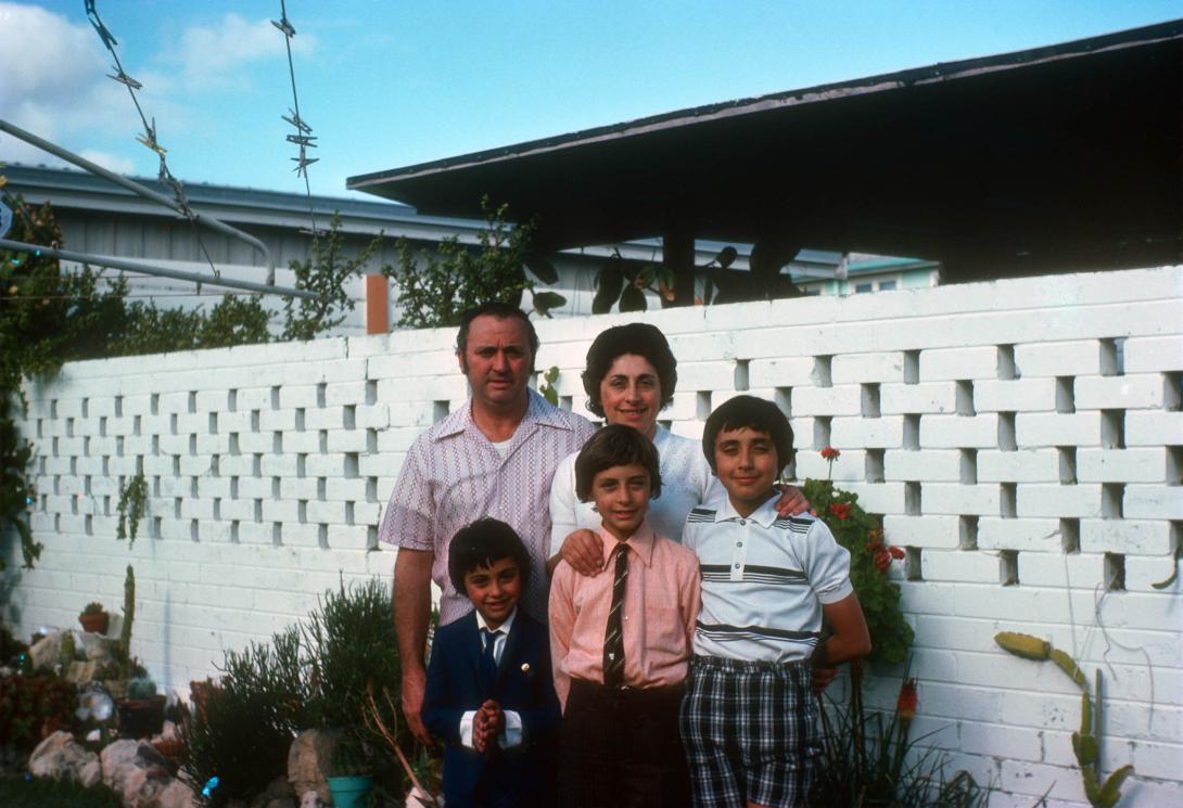 The family in front of a white painted brick wall in a suburban backyard.