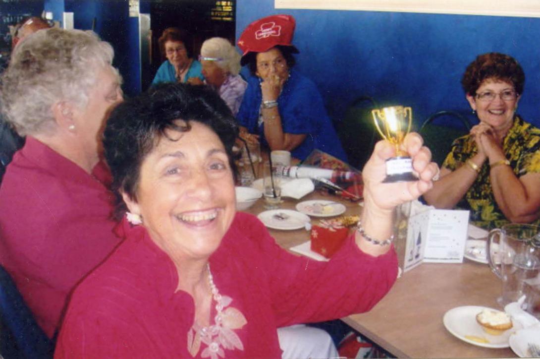A triumphant Mary holding up a tiny golden trophy.