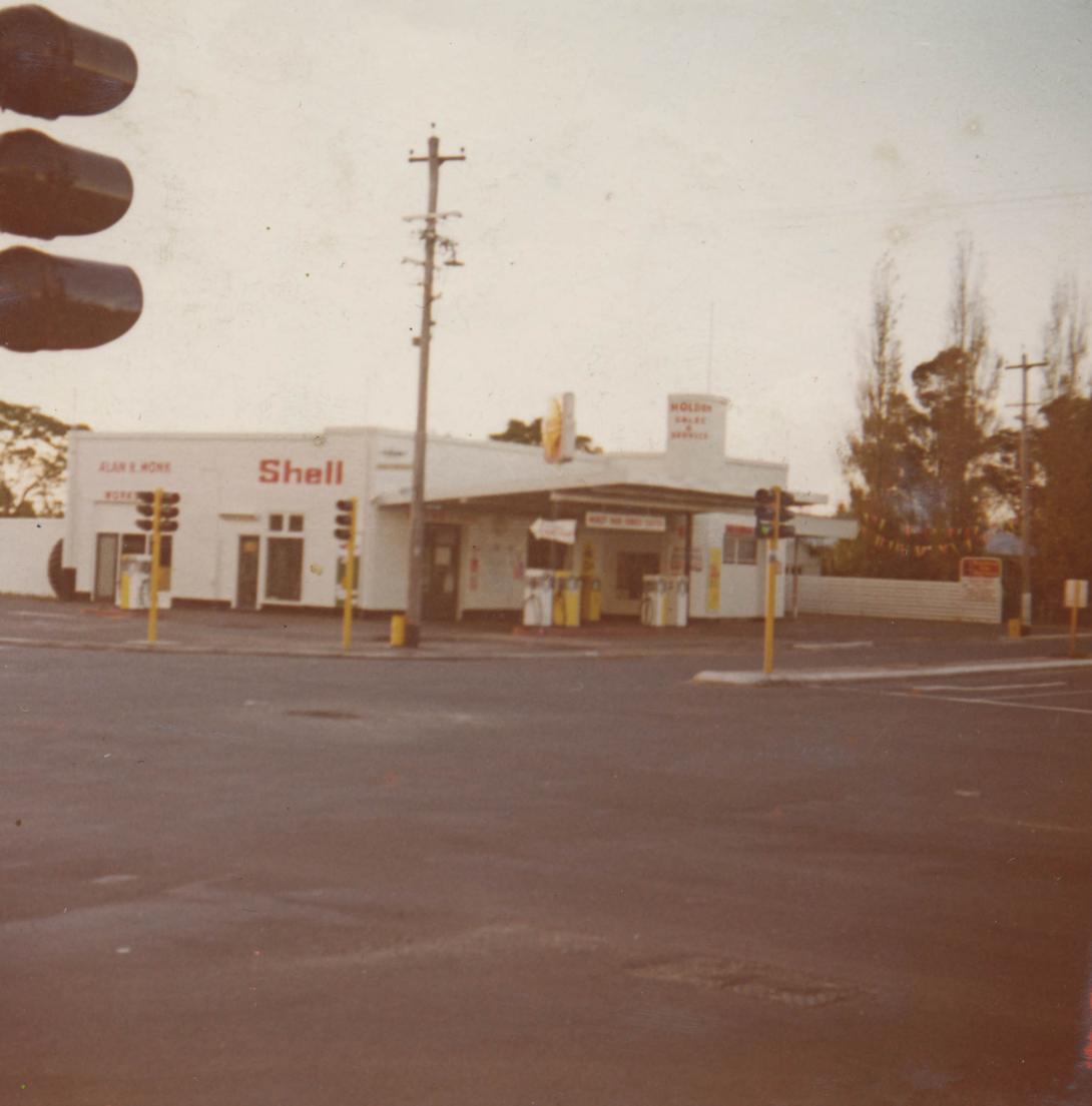 The white Shell Oil service station stands on a street corner.