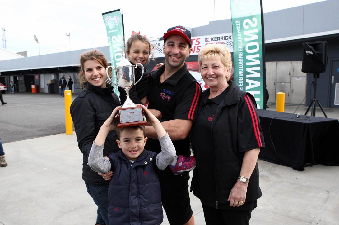 A young Tony holds a silver trophy above his head while the rest of the family grin triumphantly.