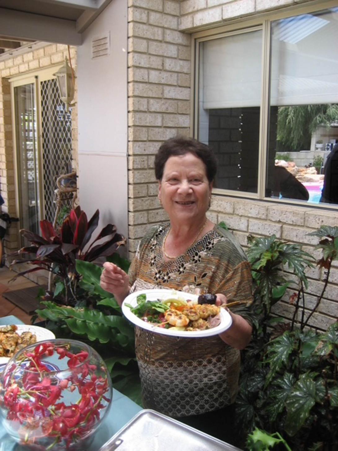 Giuseppina holding up a plate of cooked food.