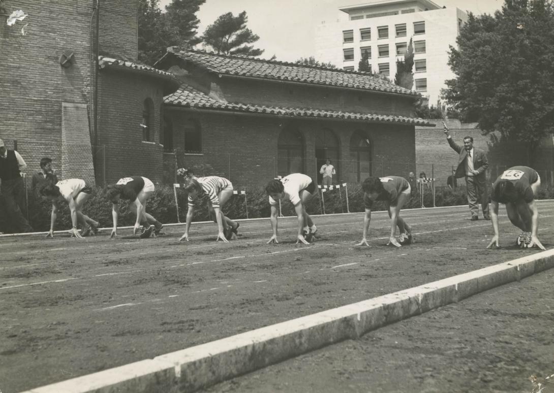 The six runners bent over, ready to spring into action as the starter pistol is raised to fire.