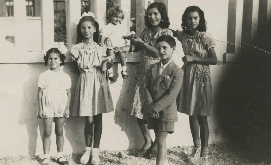 The children gathered at a white wall, the smallest perched on it holding Franca's hand.