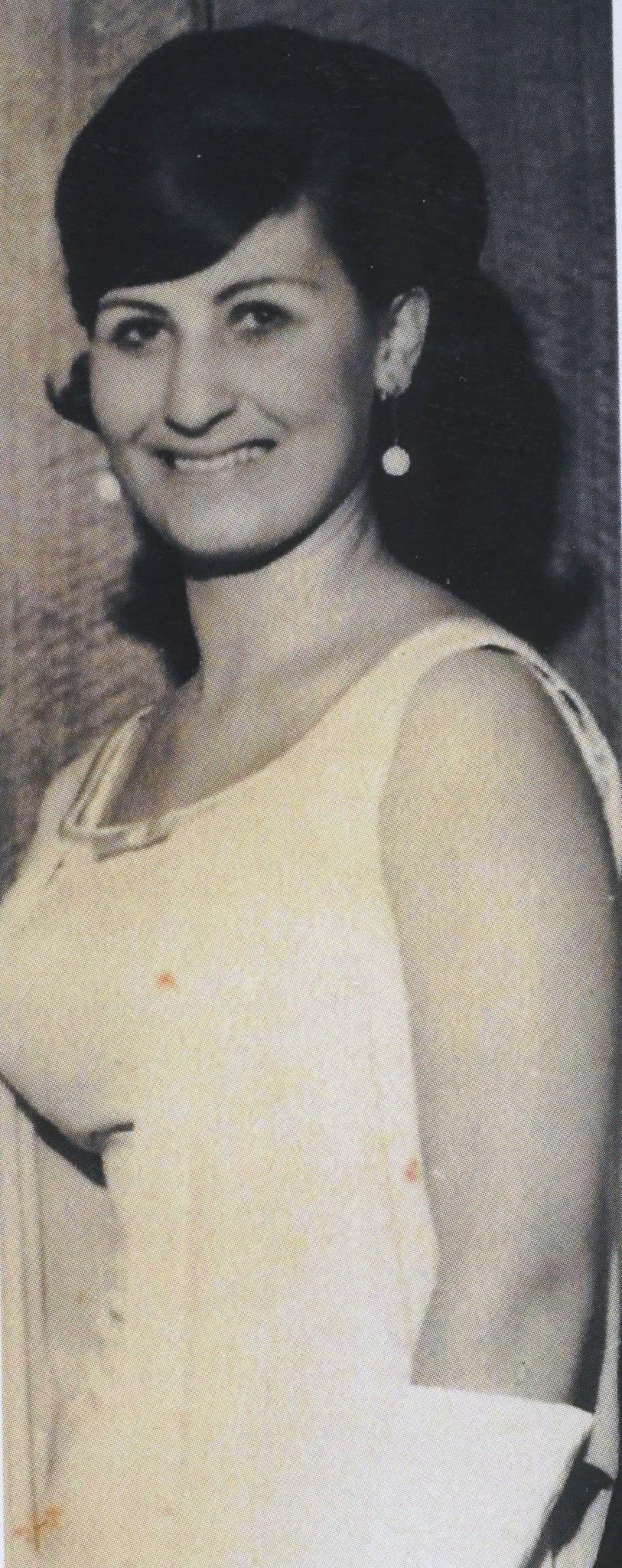 A smiling Rosie in a white sleeveless dress and long gloves.