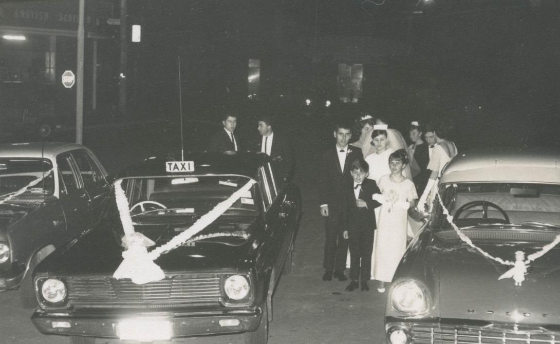 A black taxicab and a convertable with "Just Married" decorations on the bonnets.