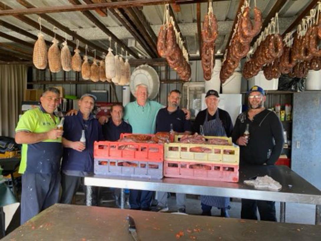 Long racks of sausages cover the ceiling. Four large trays are piled with more meat.