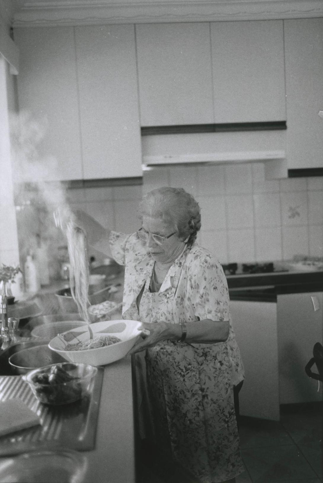 Carolina pulls up a big lump of steaming spaghetti over the kitchen sink.
