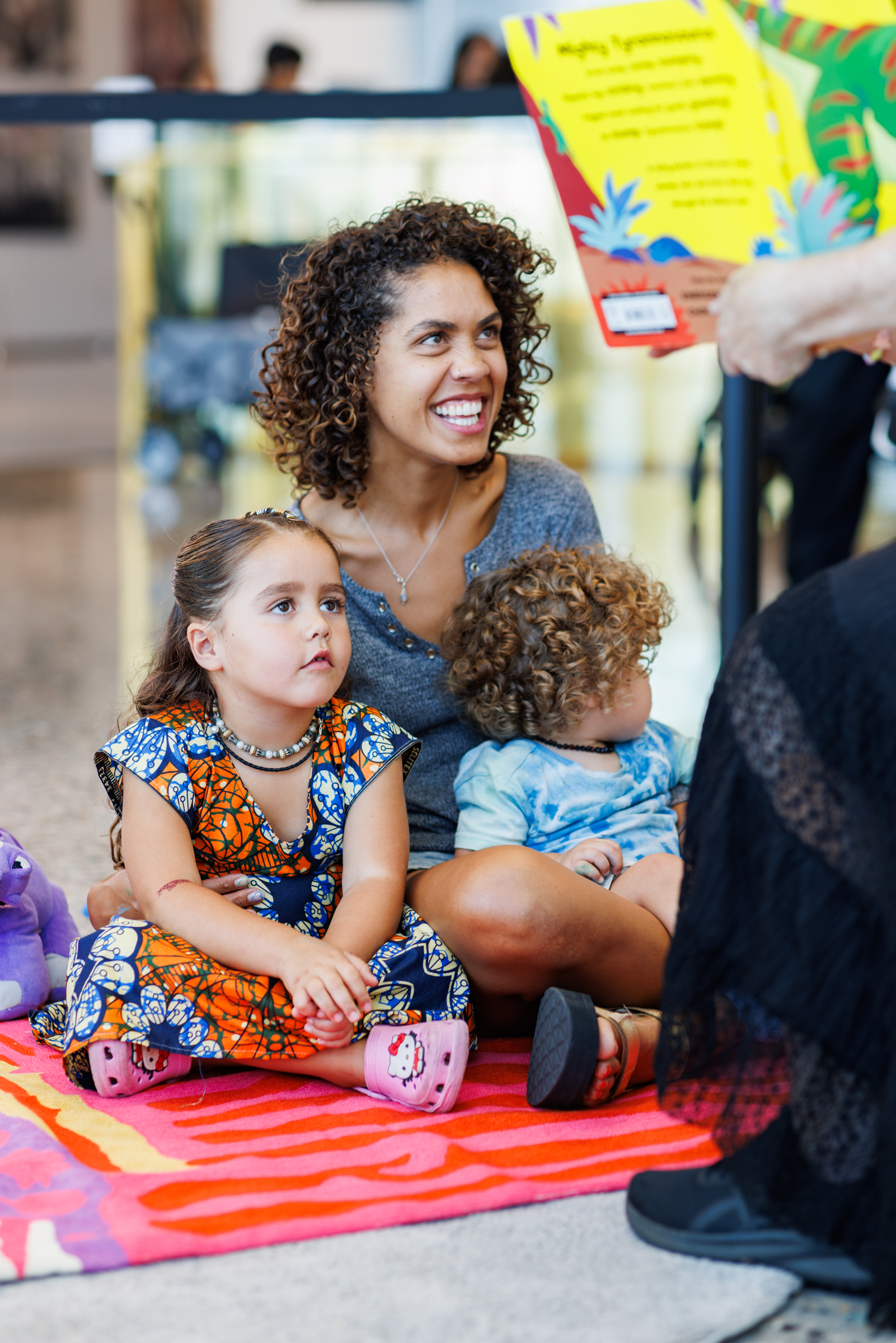 A mother and too young children, listening to story time.