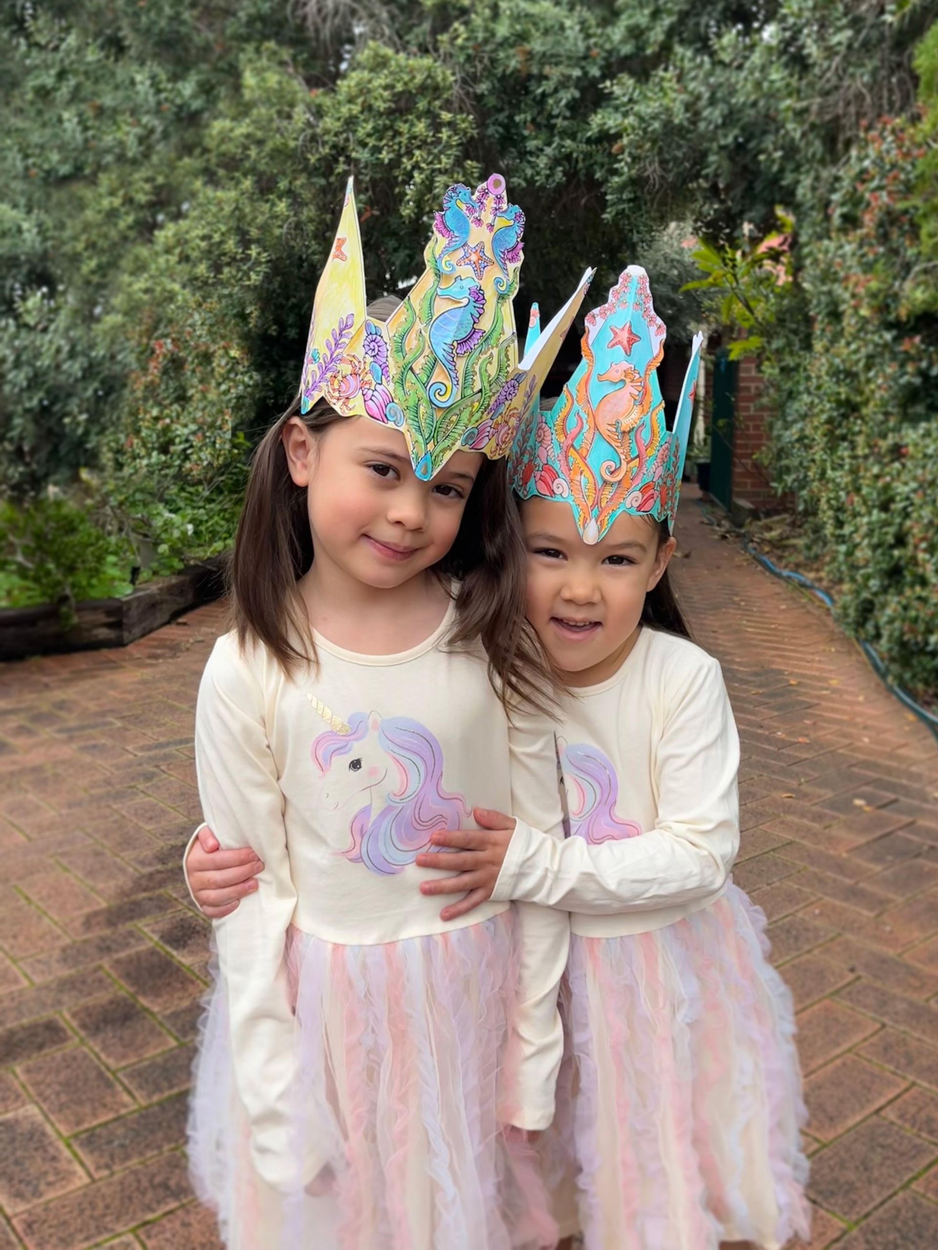 two children are wearing sea crown hats they crafted