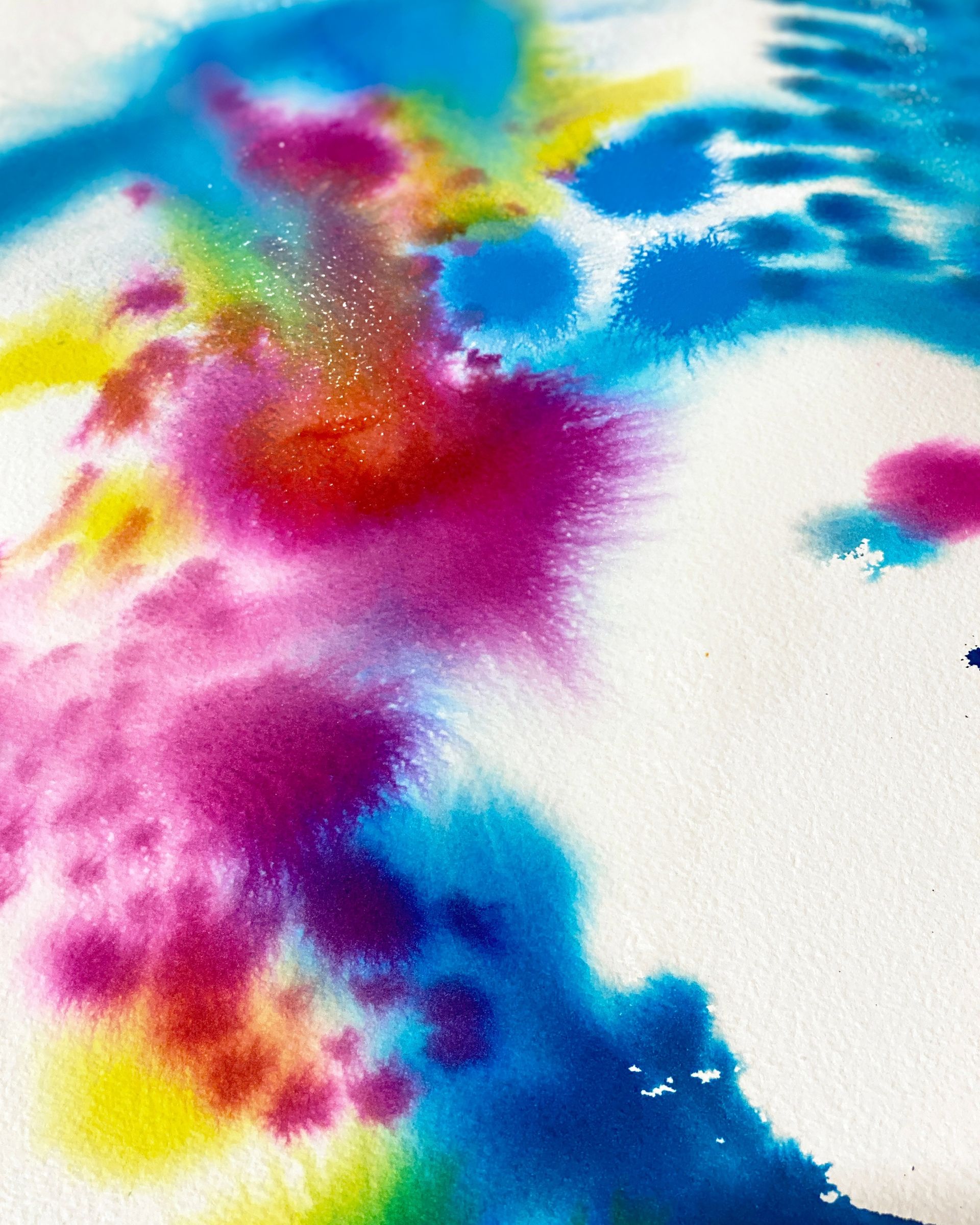a colourful abstract artwork created with inks. there are circles of pinks, blues ad some yellow