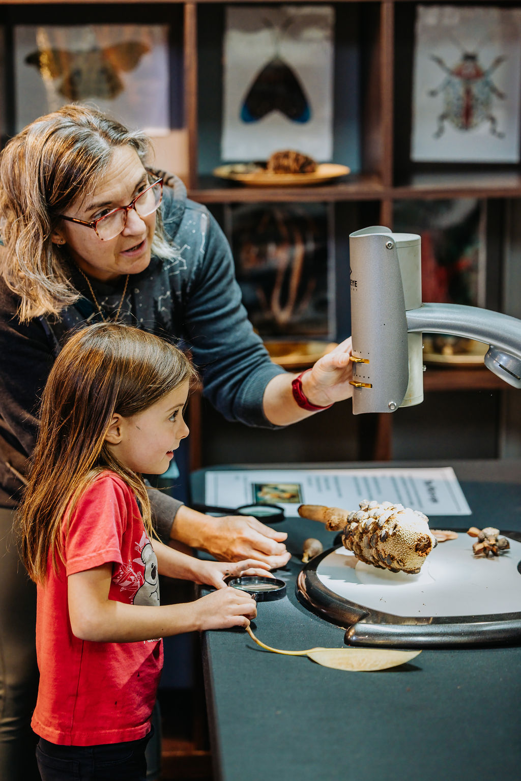 a parent and child use a microscope to look closely at some objects