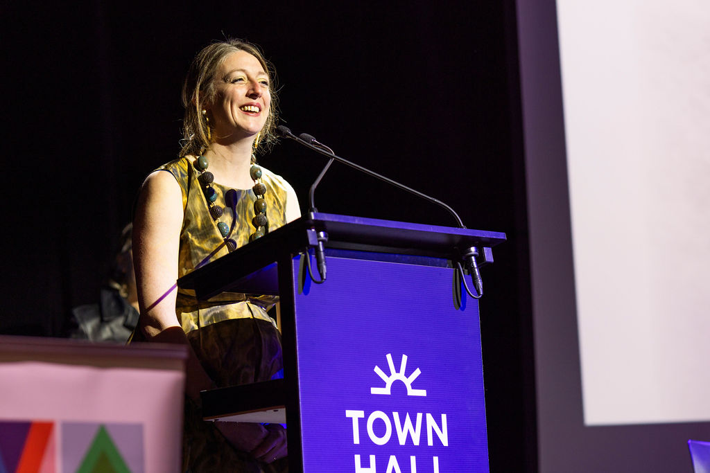 A blonde haired woman speaks at a podium