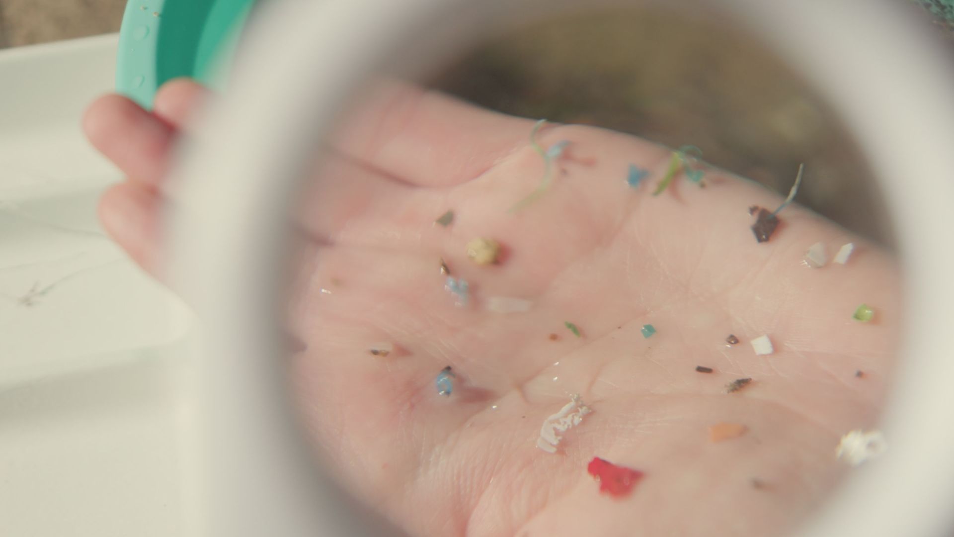 Palm of someone's hand displaying tiny pieces of multi-coloured plastic
