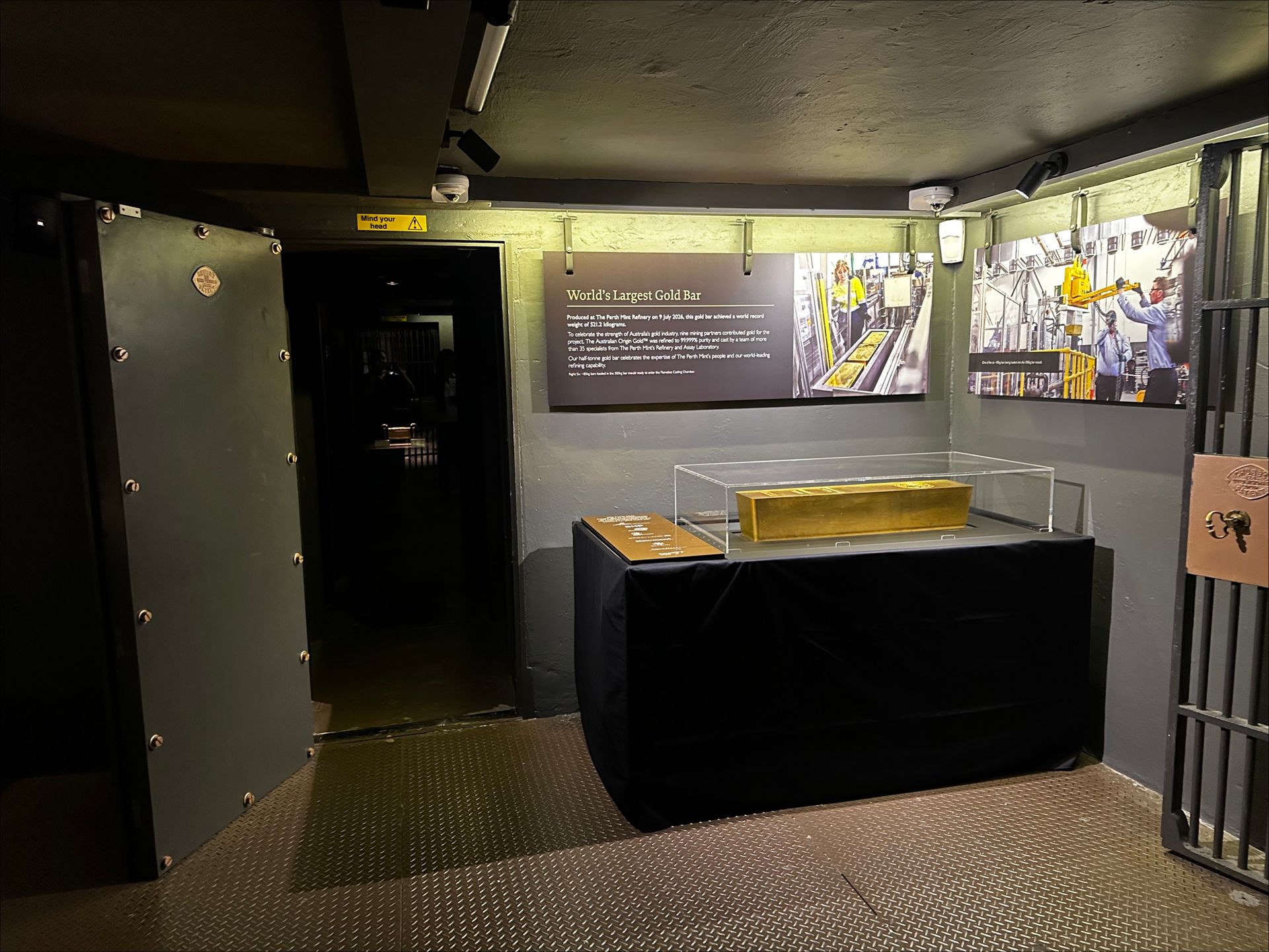 A huge gold bar is on display in a case inside a large vault