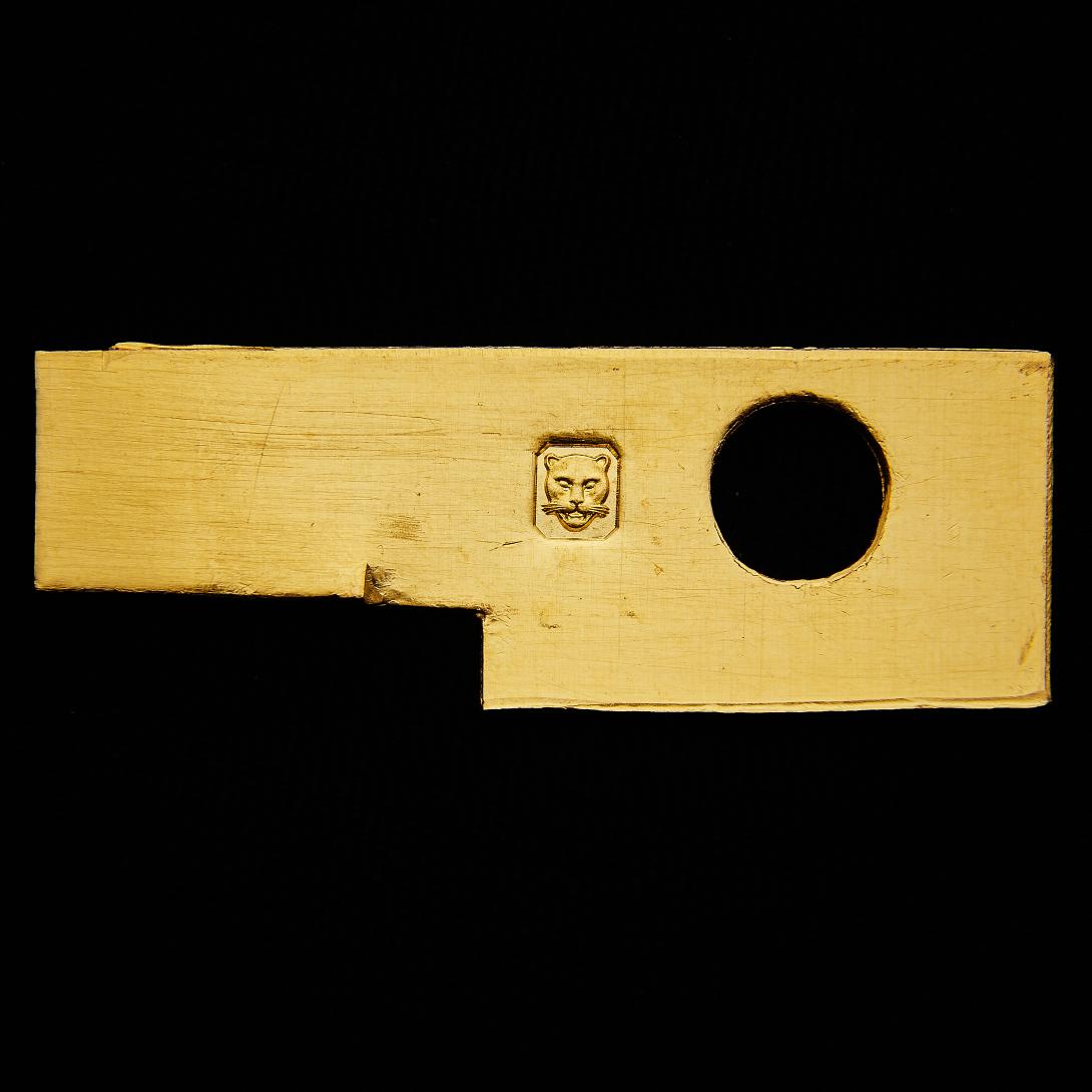 Flat gold plate with small rectangular portions cut from bottom left corner; circle cut from top right; lion stamp top centre