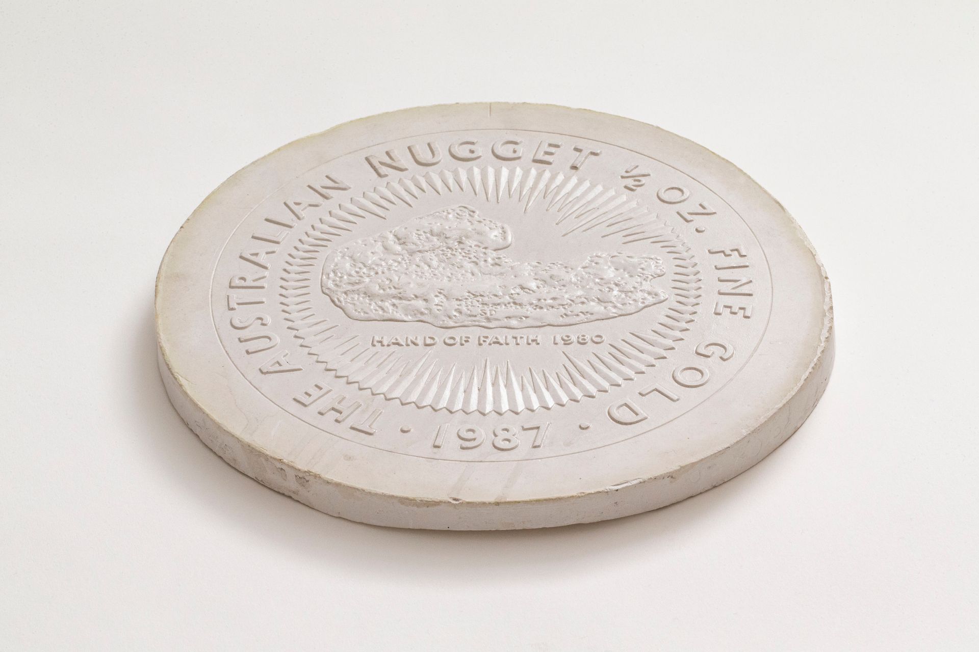 Round plaster model for a coin with inscription 'The Australian Nugget 1/2 oz Fine Gold 1987' and central design of gold nugget 'Hand of Faith 1980'