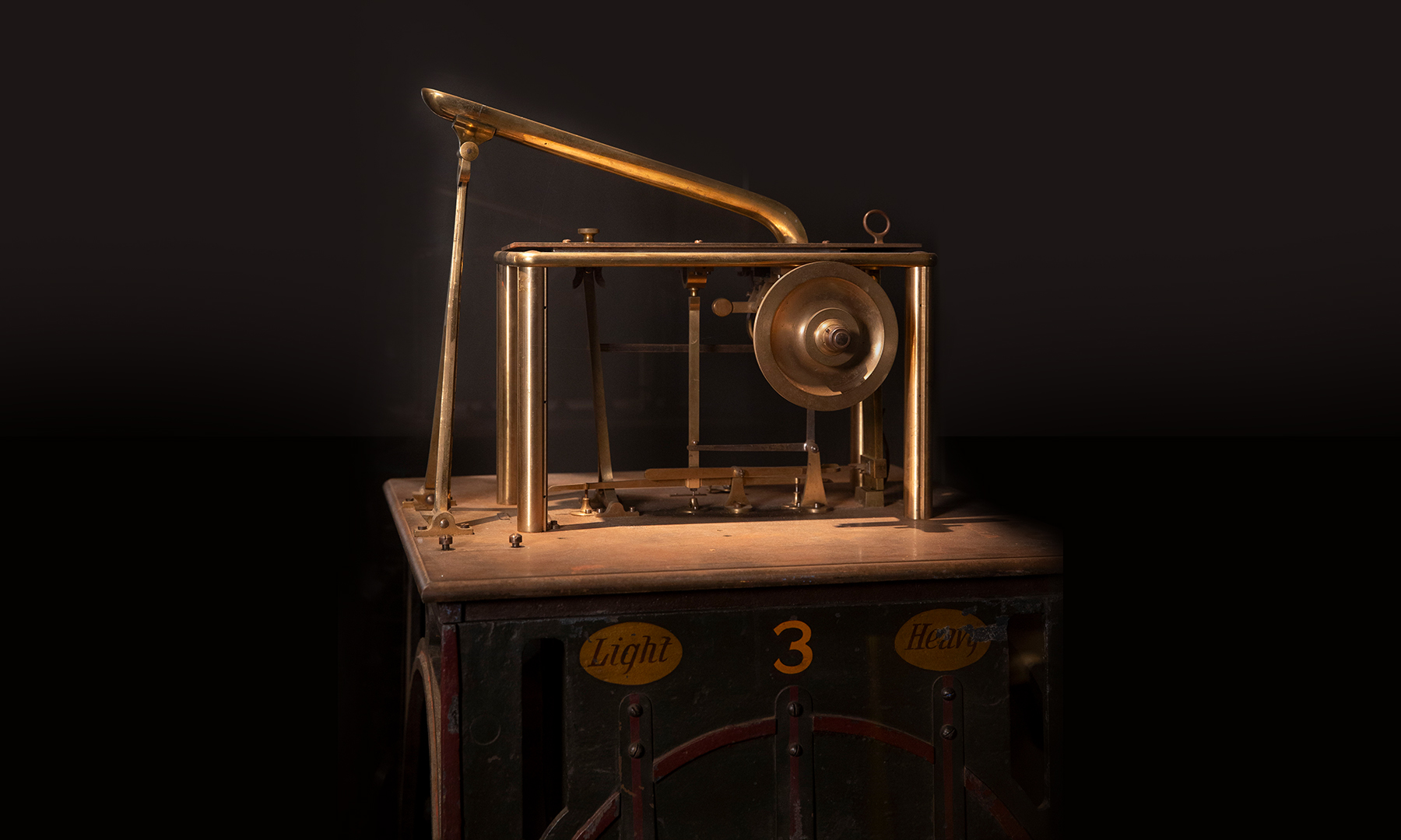 A small industrial piece of machinery with a feed chute at the top and the labels 'Light' and 'Heavy' indicating it was used for weighing