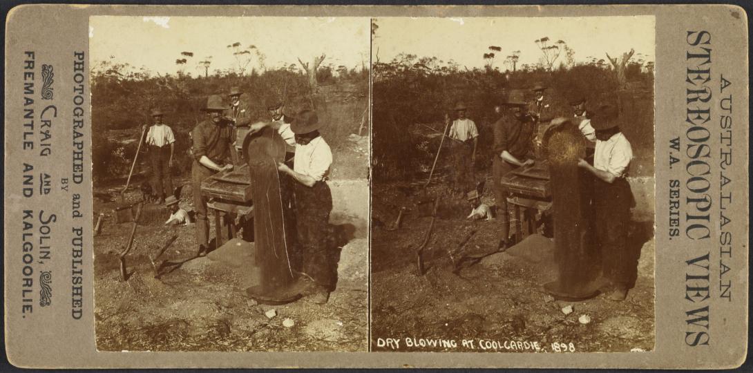 Stereoscope card by photographed and published by Craig and Solin, 'Cry Blowing at Coolgardie, 1898; card has two identical black and white photos of a group of six men in the bush - four are prospecting - one tips soil from a gold pan, another stands at a shaker machine, a third holds a long handled tool, another stands in a deep hole; the two other men who are dressed in suits watch on.