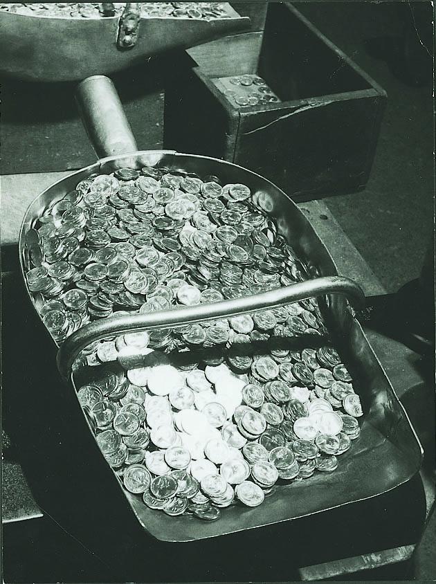 Black and white image of a large metal scoop full of Australian two cent pieces
