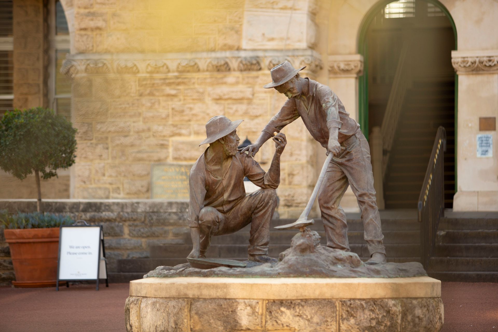 Bronze statue called 'The Strike' of two prospectors by sculptor Greg James. One figure is crouching and holding up a small gold nugget to the standing figure, who looks upon it with exciutment.