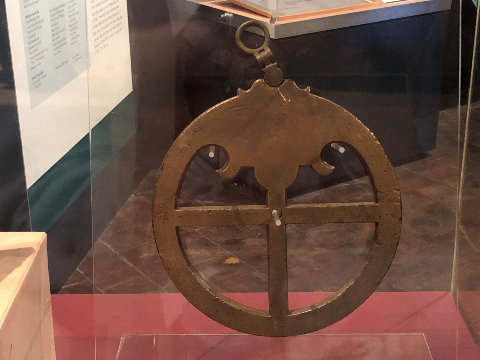Heavy brass metal circular ring with cross through the middle displayed in glass cabinet.