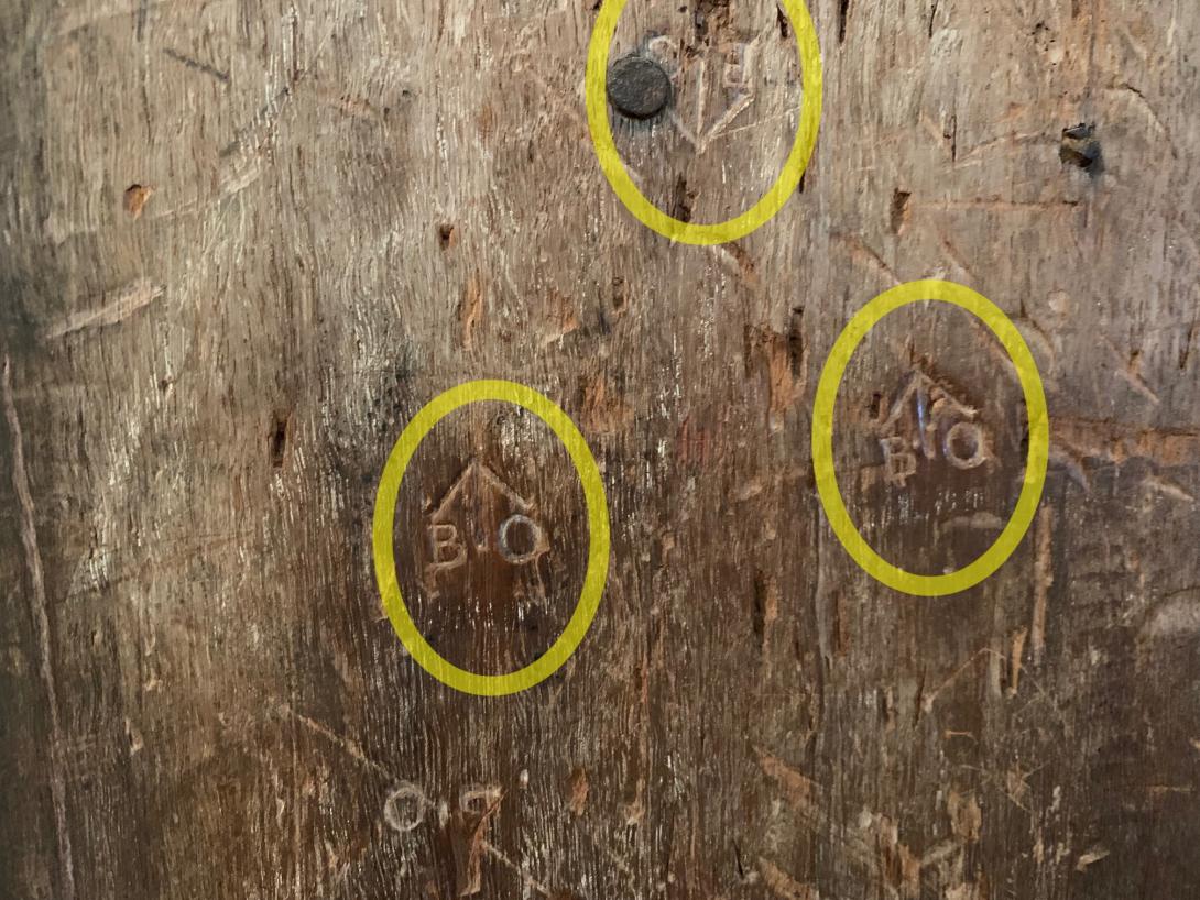 A wooden post with multiple markings of arrows and the letters B and O.