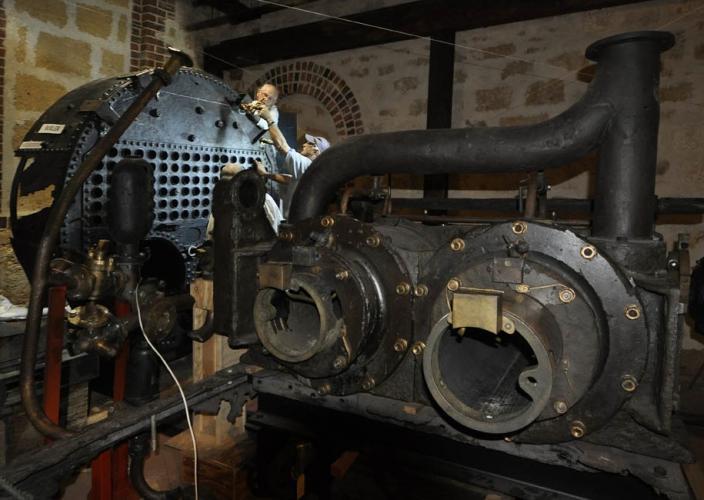 Photo of two men working on a large piece of machinery inside the Shipwrecks Museum
