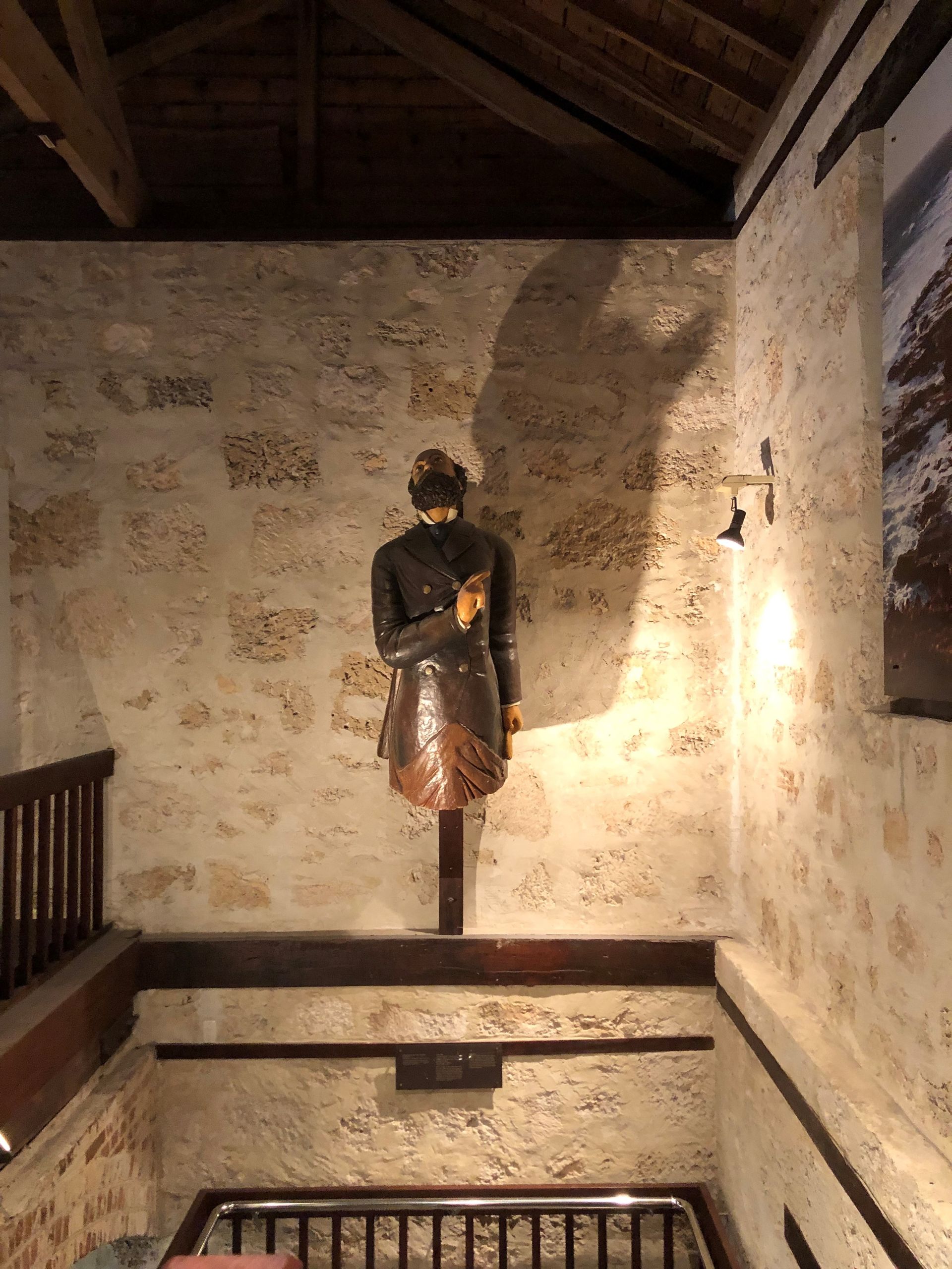 Mounted on a stone wall in the stair way is a statue of a bearded man in a formal jacket.
