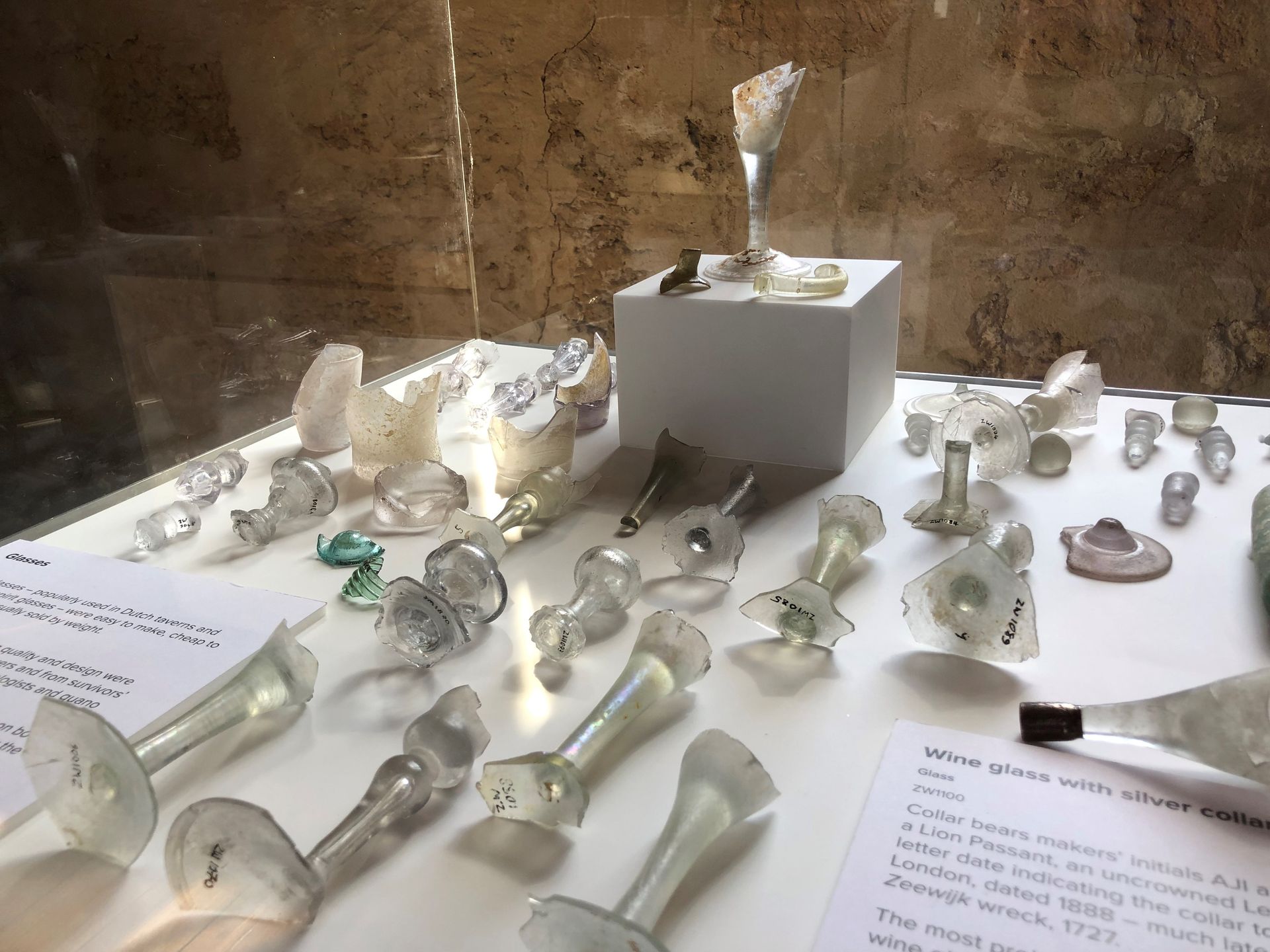 Pieces of broken glass objects laying in on a white surface in the cabinet. Some pieces are bases to wine glasses.